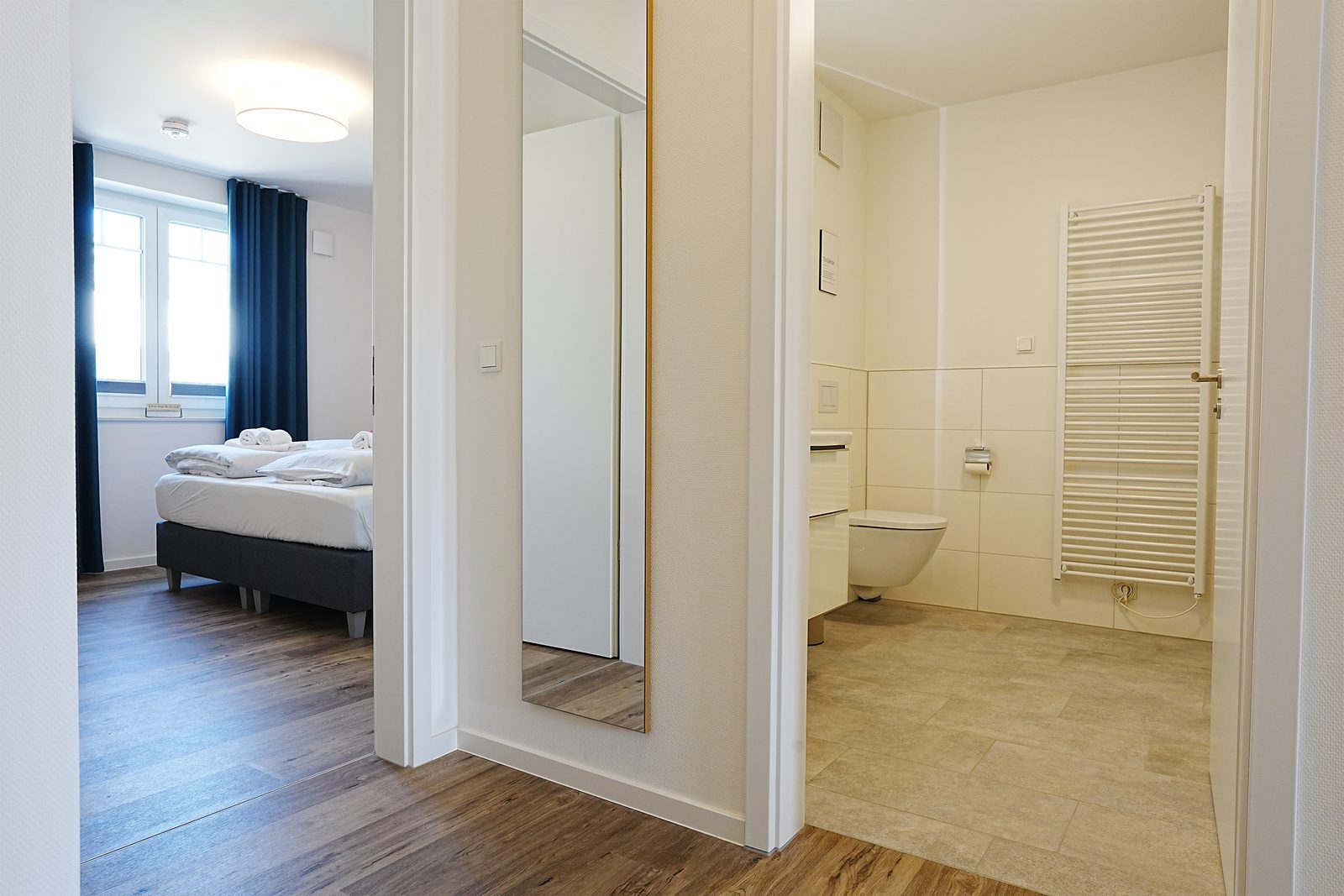 Schlafzimmer mit Blick ins Bad vorher: gedämpftes Licht.